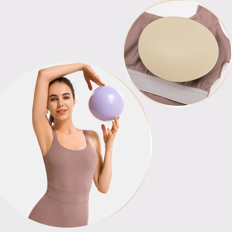 Woman in stylish elastic open back fitness jumpsuit holding a purple exercise ball, showcasing activewear comfort and flexibility.